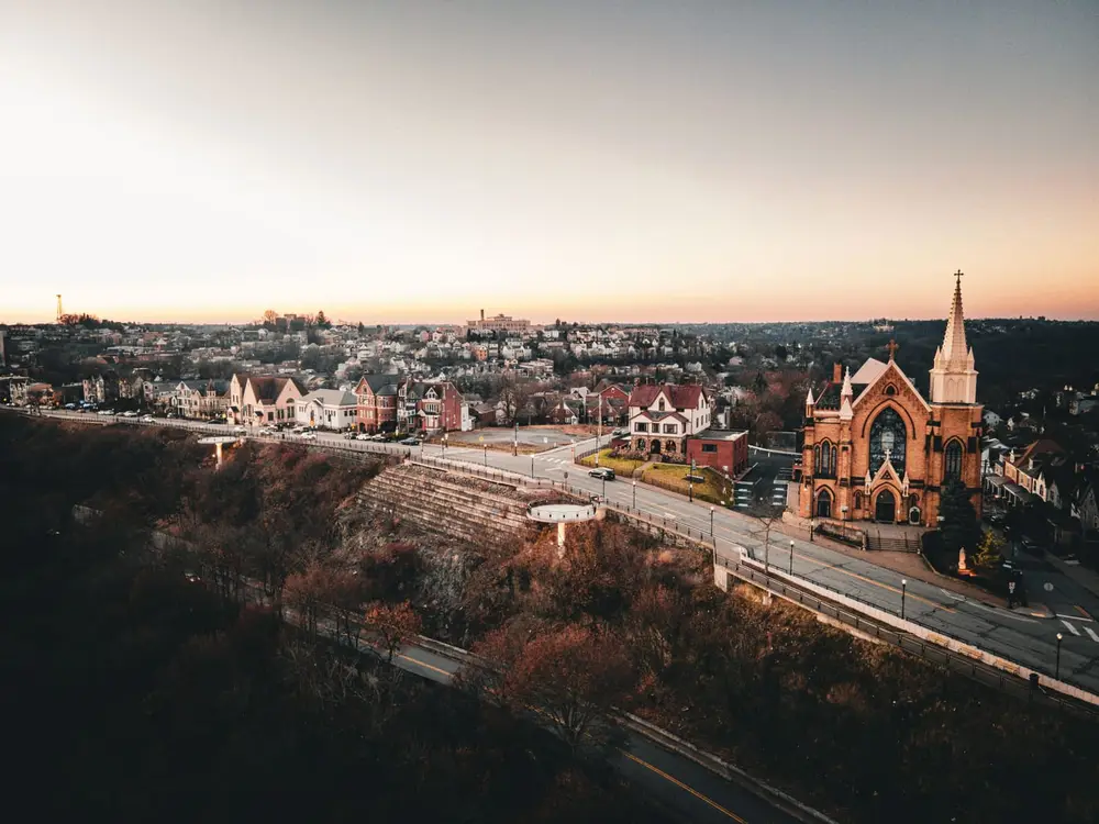 A Pittsburgh neighborhood of brick homes and a church at sunset